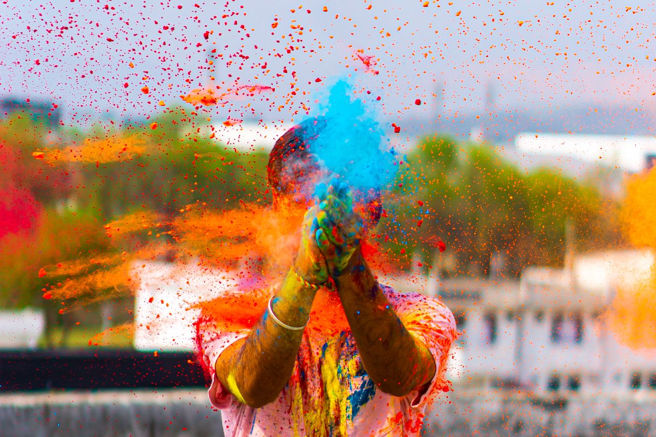 Bunte Holi-Festivalfeier mit lebhaften Pulvern, die in die Luft geworfen werden und eine lebendige Szene schaffen.