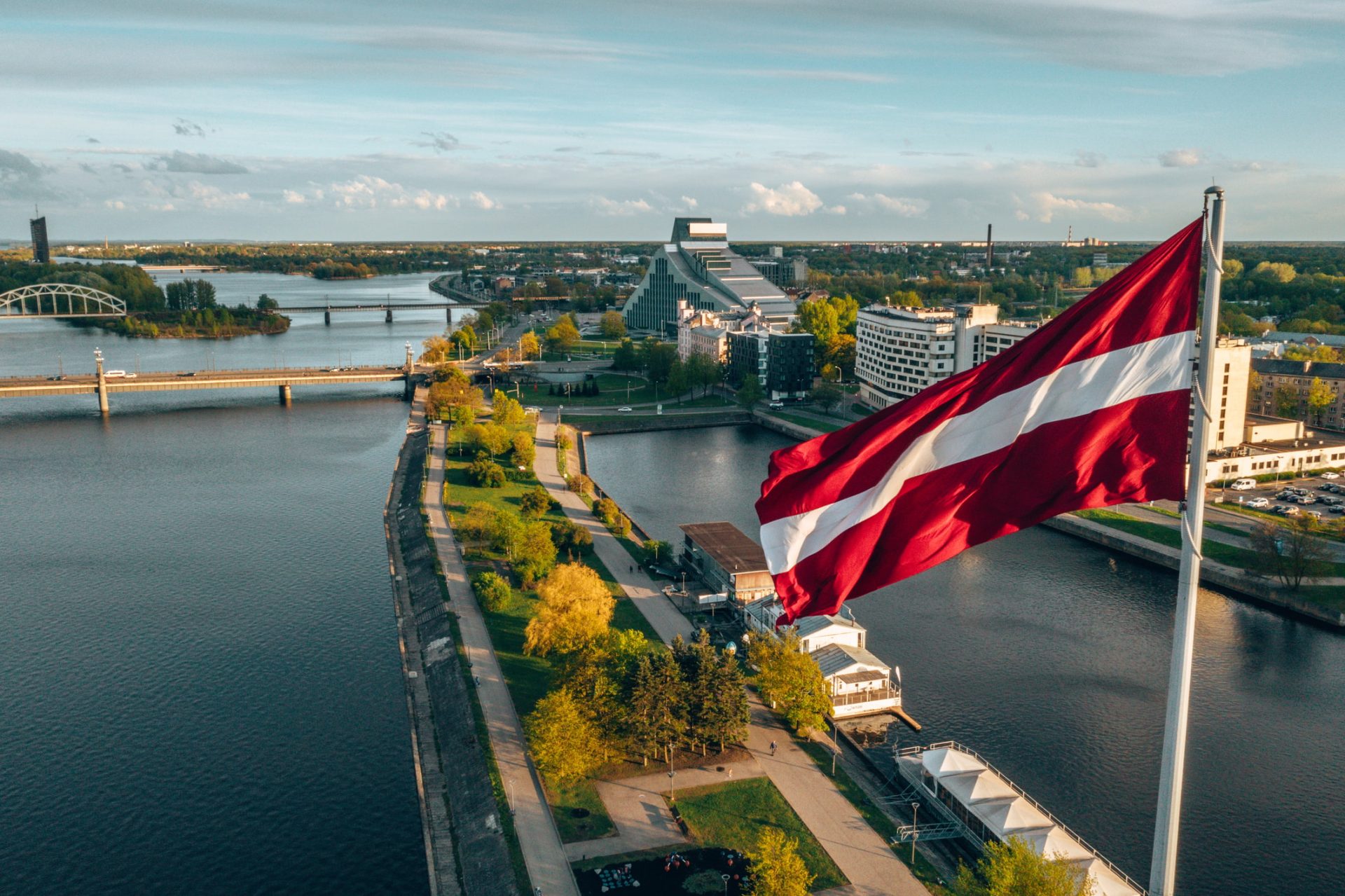 Luftbild der Stadt Riga mit einer großen lettischen Flagge im Vordergrund.