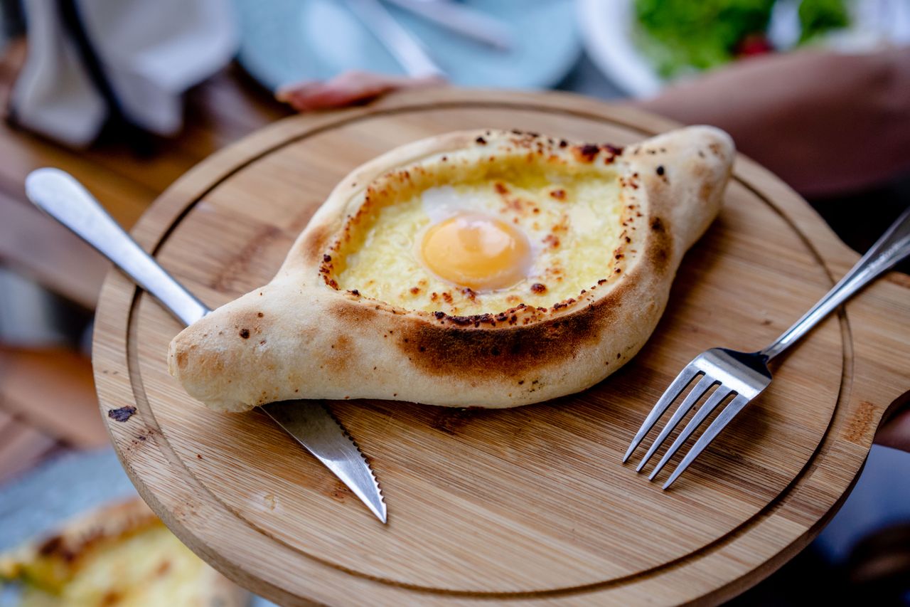 Traditionelles georgisches Khachapuri mit Ei, serviert auf einem Holzbrett