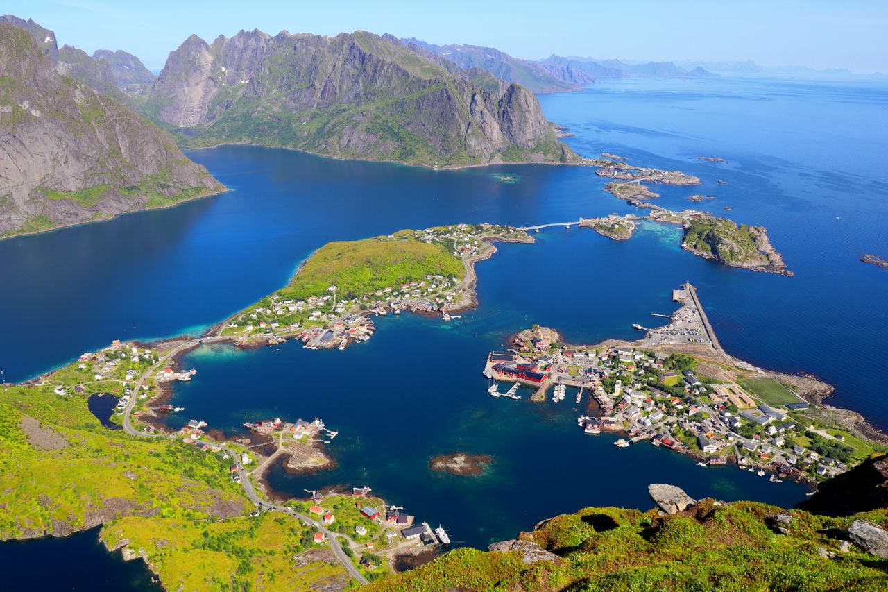 Atemberaubende Luftaufnahme eines von Bergen umgebenen Küstendorfes auf den Lofoten, Norwegen.