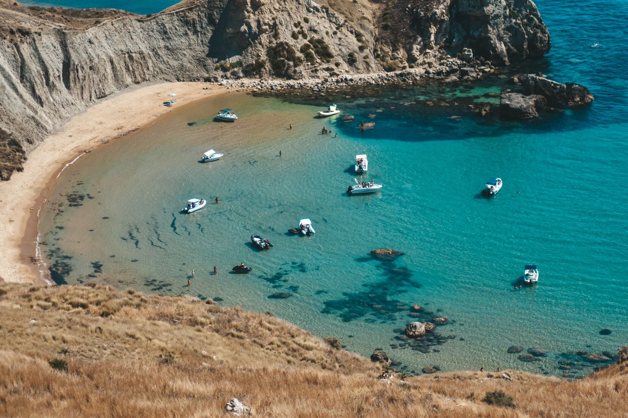 Eine malerische Strandbucht in Sizilien, Italien, mit Booten in klarem blauen Wasser. Perfekt für Reisefotos.