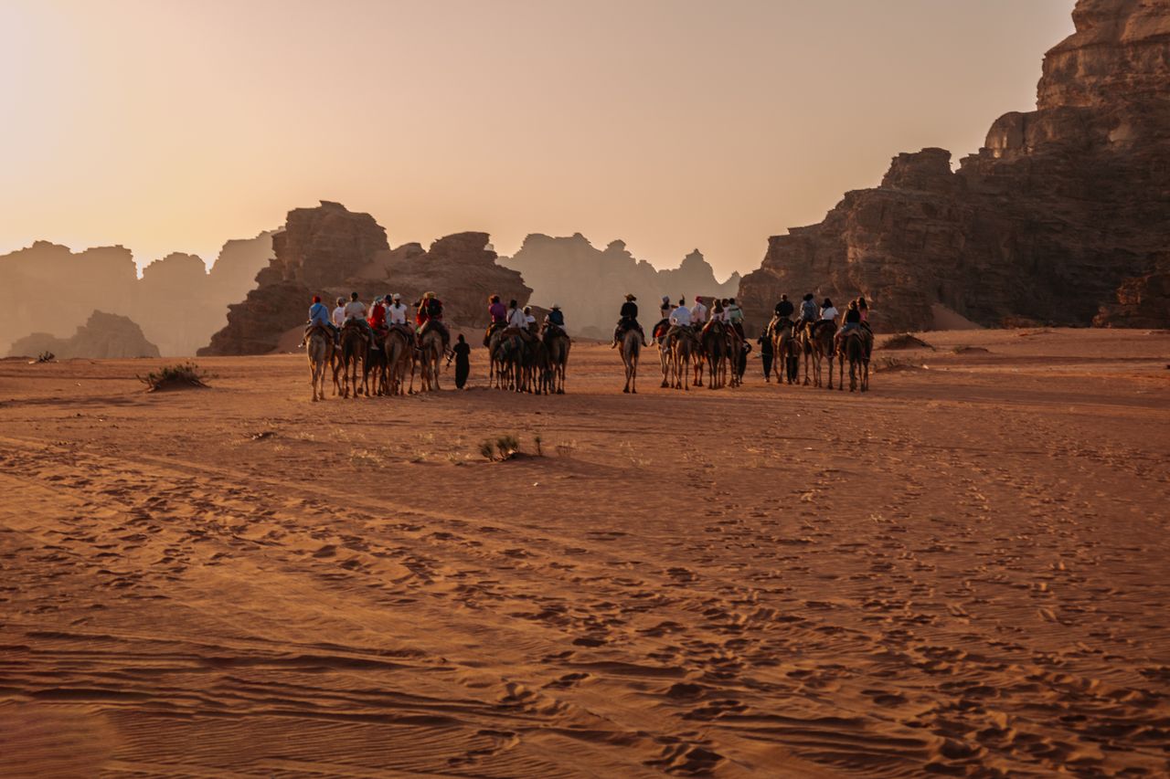 Kamelkarawane, die die atemberaubenden Landschaften der Wadi Rum Wüste bei Sonnenuntergang, Jordanien, durchquert.