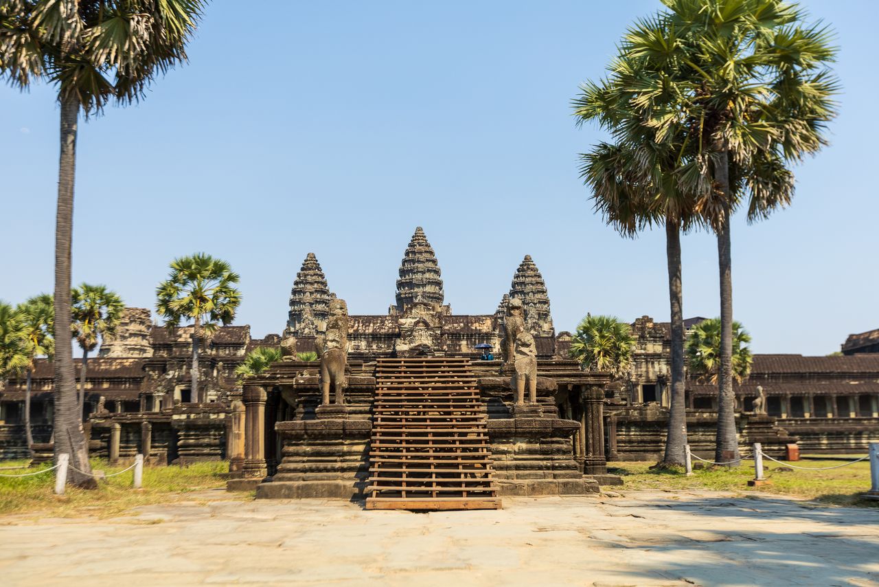 Majestätischer Blick auf den Eingang des Angkor Wat Tempels, umgeben von Palmen in Kambodscha.