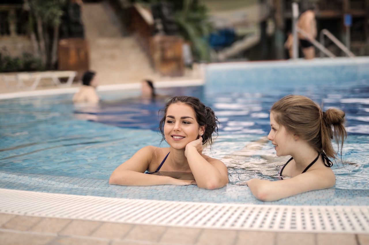 Zwei Frauen, die einen entspannten Nachmittag in einem Resort-Schwimmbecken genießen, lächelnd und entspannt.